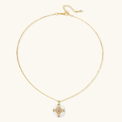 Gold-plated necklace with circular white enamel pendant featuring central zirconia stone and ornate decorative details