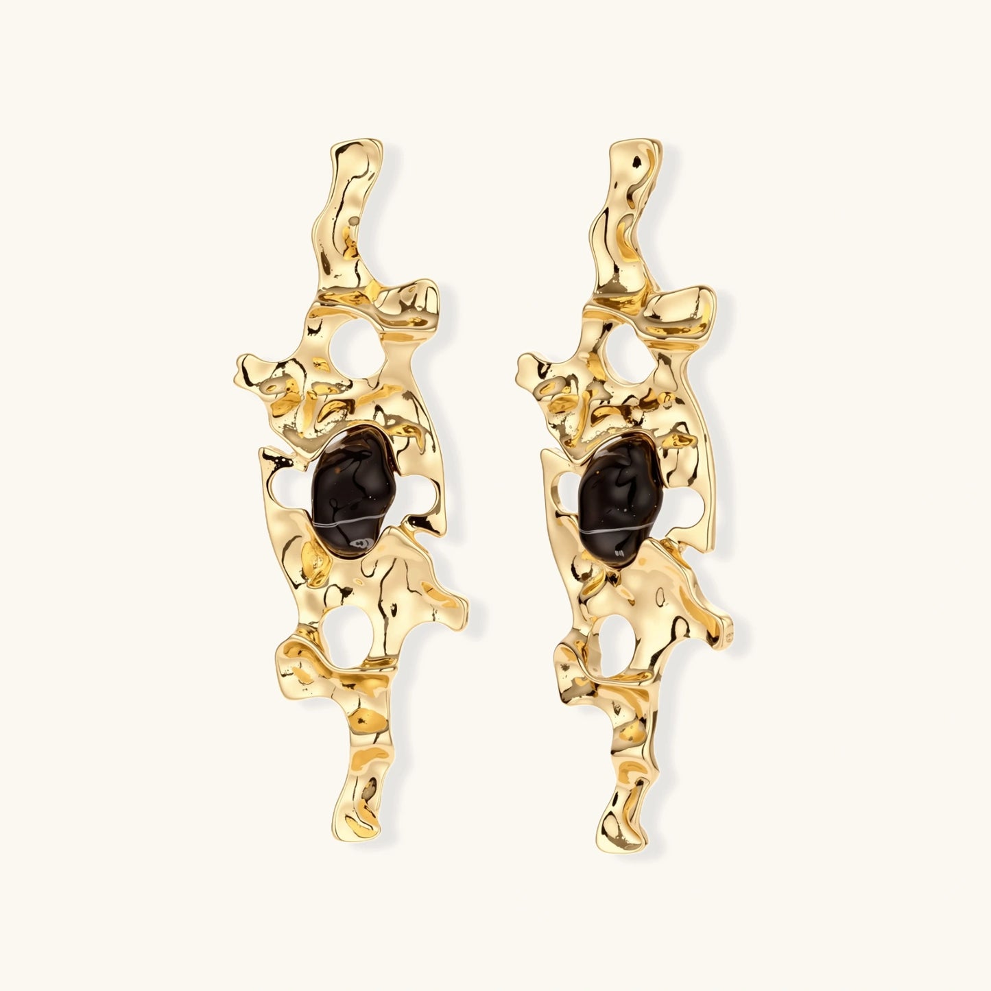 Elongated sculptural earrings with organic openwork design in eco-zinc alloy and dark resin accents on white background.