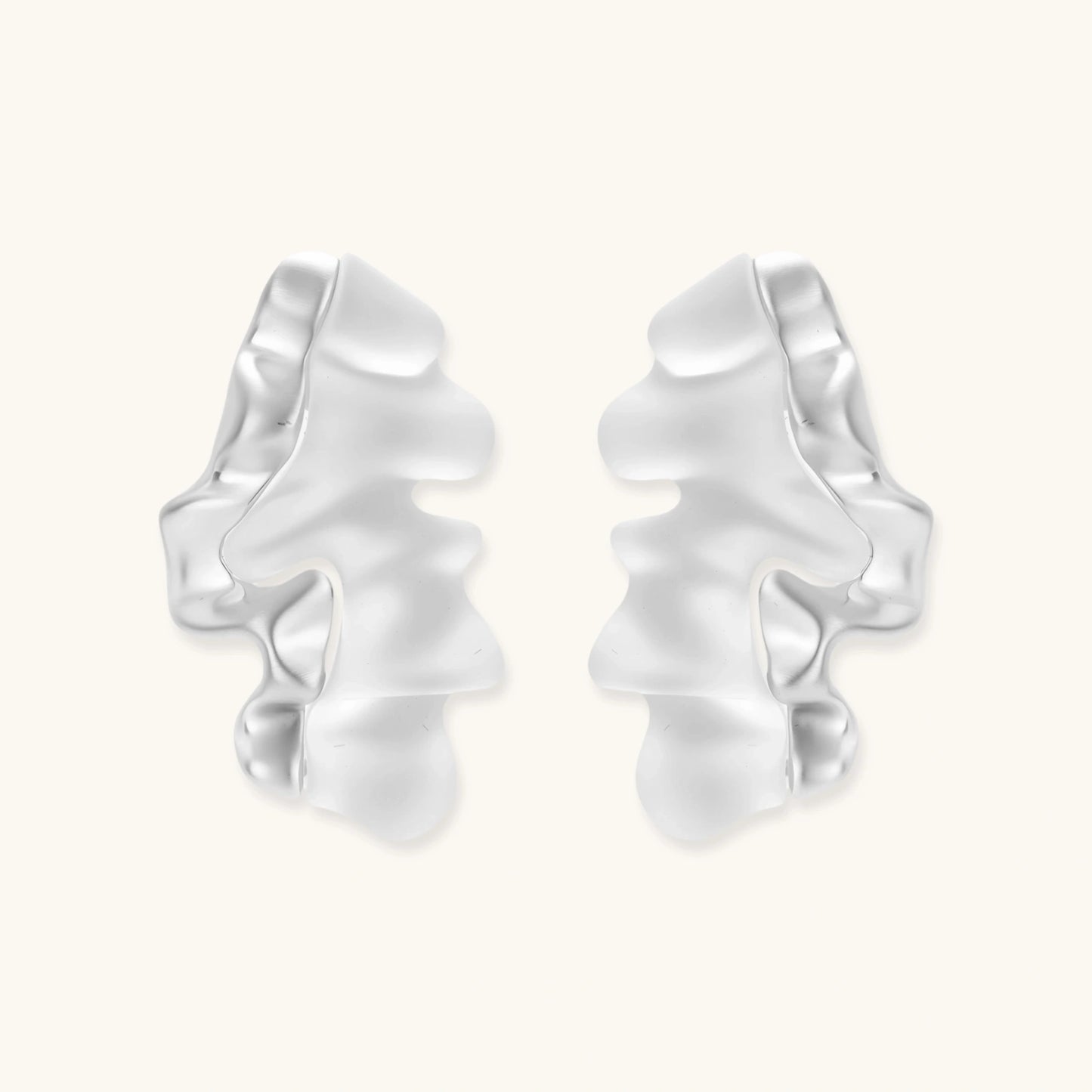 Pair of silver-toned sculptural earrings with flowing abstract forms and stud backs against white background.