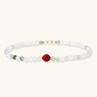 Three layered white beaded bracelets with carved orange agate lotus centerpiece and freshwater pearls on cream background.