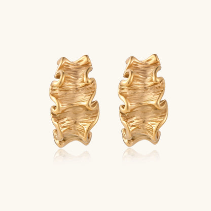 Sculptural gold hoops with textured wave patterns and rippled surface in 14K plating, shown from front and back angles