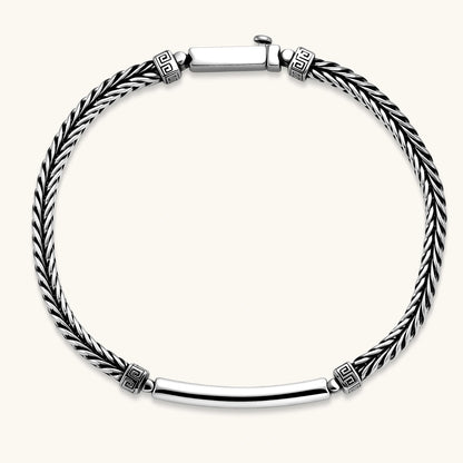 Silver stainless steel men's bracelet with braided foxtail chain, Greek key engraved bar, and decorative cube connectors.