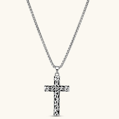 Silver stainless steel Celtic cross pendant with filigree vine pattern on a box chain, against a cream background.